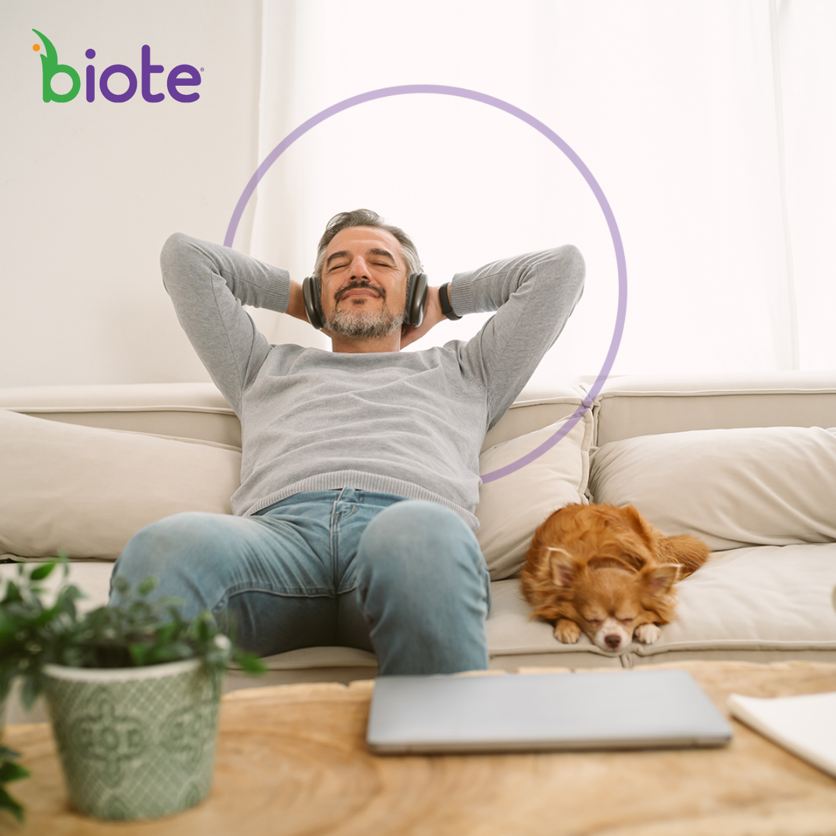 Man on a couch with his dog next to him listening to music